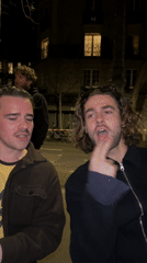 Young men photographed socializing outdoors at night in Paris