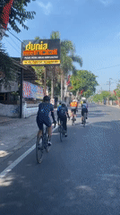 Cyclists ride in formation through flag-lined streets of Kediri