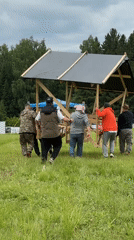 Camping group constructs wooden structures in Russian countryside field