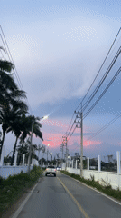 Car drives through Pattaya at dusk under pink-streaked sunset