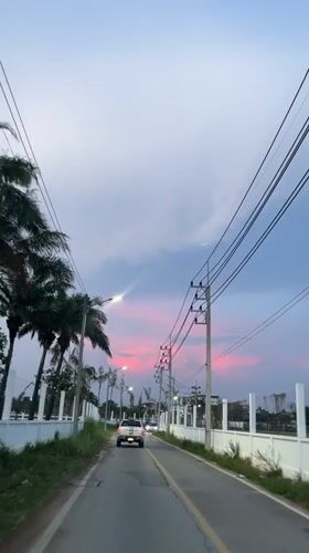 Car drives through Pattaya at dusk under pink-streaked sunset