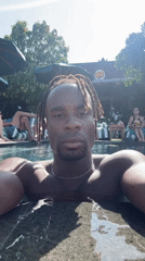 Man with dreadlocks enjoys morning swim at tropical resort
