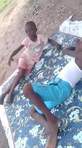 Kids on a mattress, shirtless figure outdoors near blue windows