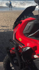 Man sits on motorcycle watching beach activity in Canggu