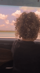 Child travels by car along Indonesian coast during dawn
