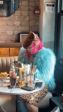 Pink-haired woman waves in London cafe, group gathers nearby