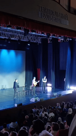 Suited ensemble performs live on a theater stage