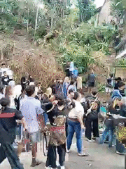 Man searches ground before crowd near wooded area