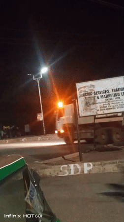 Nighttime street hustle: tuk-tuks, overloaded cars, and roadside grilling
