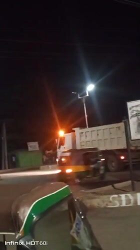 Nighttime street hustle: tuk-tuks, overloaded cars, and roadside grilling