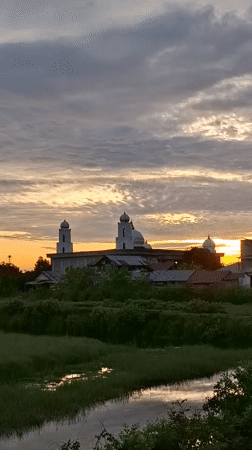 Sunset silhouettes mosque in Indonesian village, tanker truck nearby