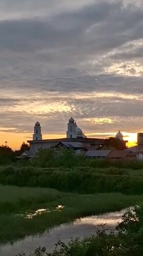 Sunset silhouettes mosque in Indonesian village, tanker truck nearby