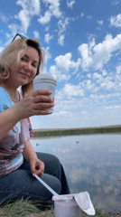 Woman enjoys lakeside breakfast on quiet Russian morning