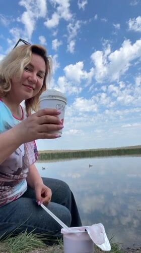 Woman enjoys lakeside breakfast on quiet Russian morning