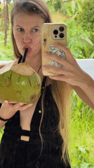 Tourist takes selfies with coconut drink in tropical Tabanan