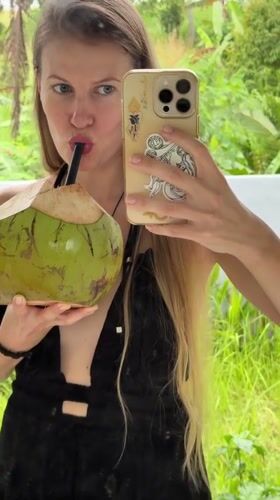 Tourist takes selfies with coconut drink in tropical Tabanan