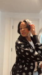 Woman in polka dot hoodie styles hair in London morning