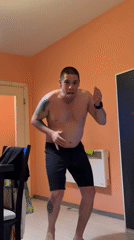 Tattooed man dances shirtless indoors in Sofia room