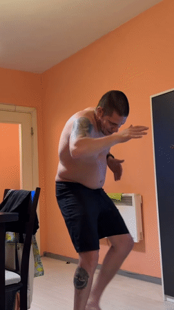 Tattooed man dances shirtless indoors in Sofia room