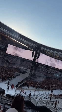 Packed Madrid stadium concert, crowd lit up with light sticks