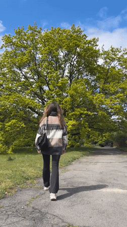 Woman climbs birch tree in Ukrainian park during morning walk