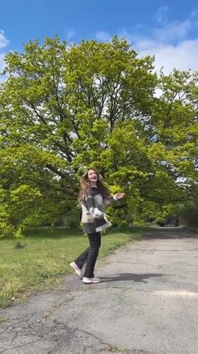 Woman climbs birch tree in Ukrainian park during morning walk