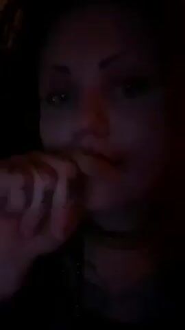 A close-up, low-lit video shows a fair-skinned woman. She is wearing red lipstick, a choker, and a necklace. The woman's hand is near her face. She speaks and appears to be recording a video.