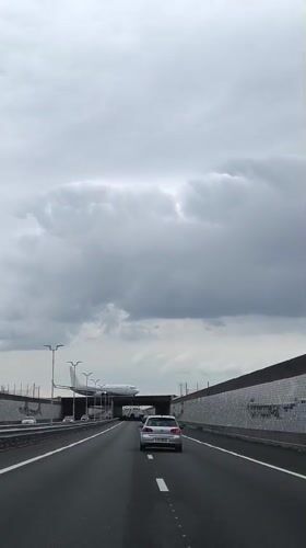 Car approaches tunnel as airplane passes overhead in Netherlands
