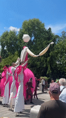 Stilt performers entertain crowds near fountain in sunny square