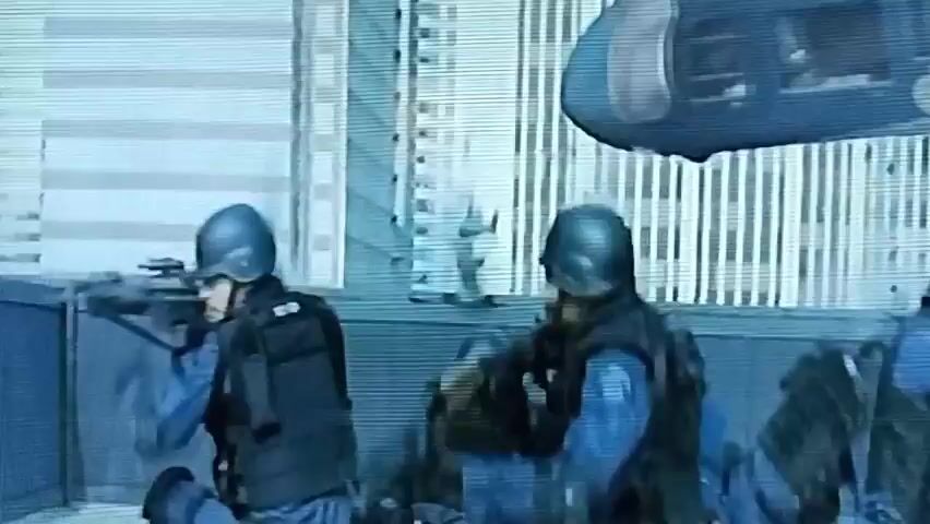 The video begins with a person in tactical gear, wearing a helmet, running in what appears to be an urban environment. Debris is seen flying in the background, suggesting an ongoing event. The scene then shifts to a close-up of an explosion, with smoke and debris erupting from a structure. Following this, a helicopter is seen falling from the sky, enveloped in smoke. The final shot provides a view from inside a helicopter cockpit, showing two individuals in helmets. The overall impression is that of a chaotic and dangerous situation, possibly an attack or disaster.