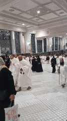 Large crowd gathers in mosque, men in white, women in black