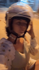 Woman adjusts helmet while riding scooter in Mũi Né