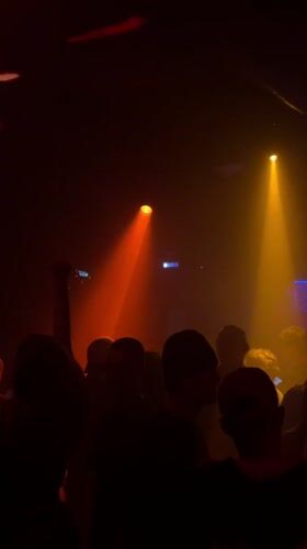 Moscow nightclub scene with dancing crowd under colored spotlights