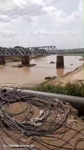Metal bridge over muddy river observed in Barnawa, Nigeria