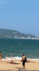 Morning at Nha Trang's Happy Beach: swimmers, wingsurfer, colorful huts