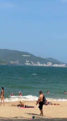 Morning at Nha Trang's Happy Beach: swimmers, wingsurfer, colorful huts