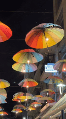 Illuminated rainbow umbrella canopy brightens Karditsa street at night