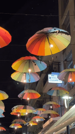 Illuminated rainbow umbrella canopy brightens Karditsa street at night