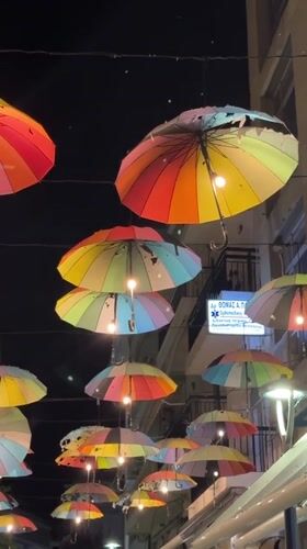 Illuminated rainbow umbrella canopy brightens Karditsa street at night