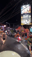 Wet nighttime street scene captured in bustling Kuta, Indonesia
