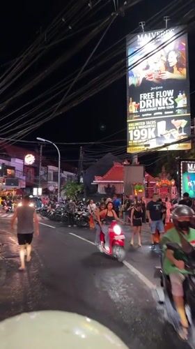 Wet nighttime street scene captured in bustling Kuta, Indonesia