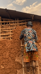 Man repairs mud house wall in Ufueseni, Nigeria