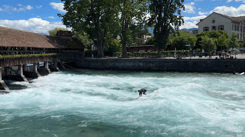 Wakeboarding on Aare River near historic bridge in Thun
