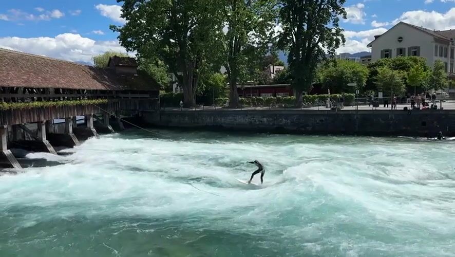 Wakeboarding on Aare River near historic bridge in Thun