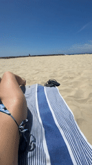 Woman sunbathes on striped towel at Herzliya beach
