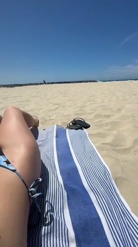 Woman sunbathes on striped towel at Herzliya beach