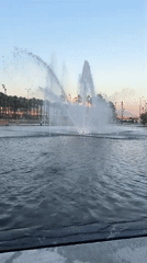 Modern plaza fountains and architecture at golden hour