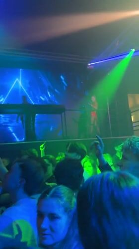 DJ performs at crowded Prague venue with colorful lighting