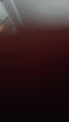 The video displays a dark red surface with varying light and shadow. The texture appears to be slightly uneven, with some subtle speckling or grain visible, particularly in brighter areas. The lighting suggests the surface is illuminated from the upper left, casting softer shadows toward the bottom right. There are no discernible people, objects, or actions within the frame; the video appears to focus solely on the textural and chromatic qualities of the surface.