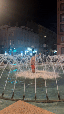 Man in red trunks enters illuminated fountain in Rijeka